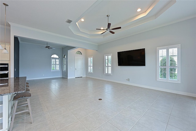 unfurnished living room with ceiling fan, visible vents, and a tray ceiling