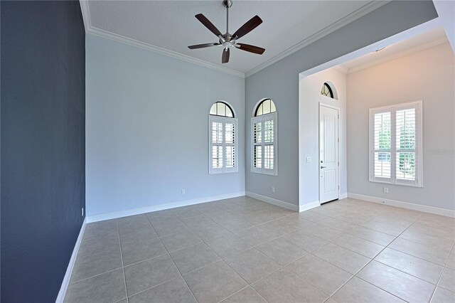 empty room featuring ceiling fan, ornamental molding, light tile patterned flooring, and baseboards