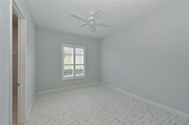 spare room with a ceiling fan and baseboards