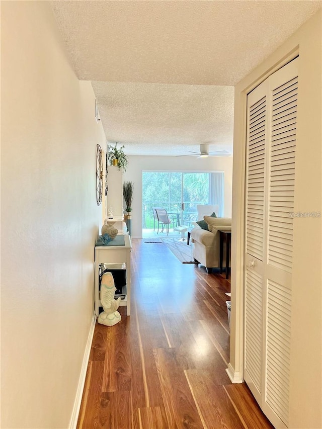 corridor with a textured ceiling and hardwood / wood-style flooring