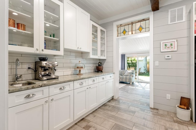 kitchen featuring white cabinets, light stone countertops, sink, and tasteful backsplash