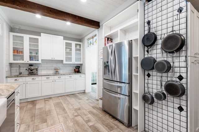 kitchen featuring beam ceiling, white cabinetry, light stone countertops, decorative backsplash, and appliances with stainless steel finishes