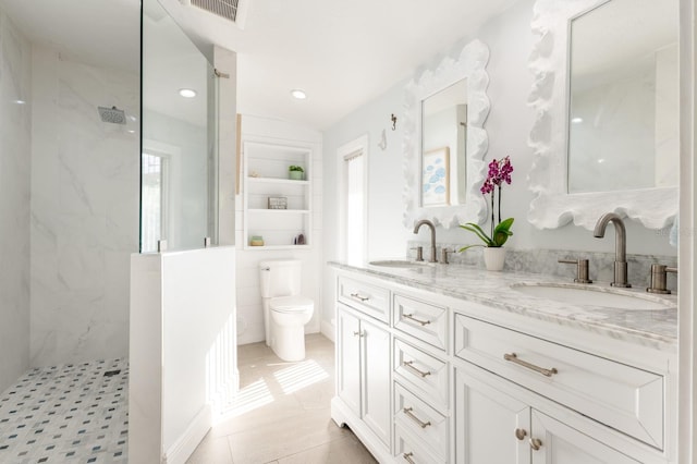 bathroom with a tile shower, vanity, a healthy amount of sunlight, and toilet