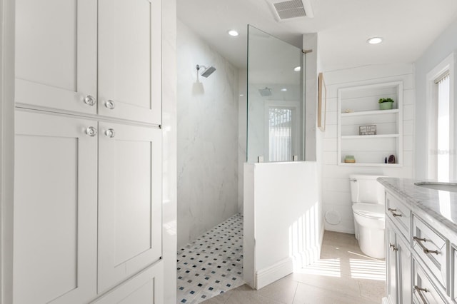 bathroom featuring built in features, tile patterned floors, toilet, tiled shower, and vanity