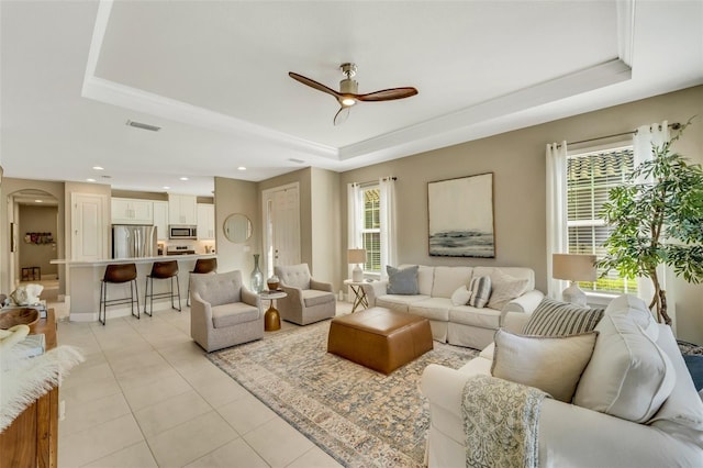 living room featuring ceiling fan, a wealth of natural light, and a tray ceiling