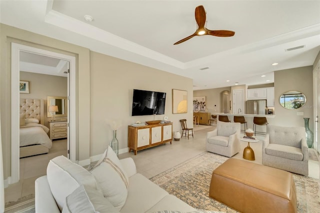 tiled living room featuring a tray ceiling and ceiling fan