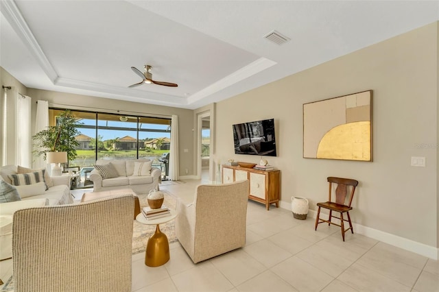 living room with ceiling fan, a raised ceiling, light tile patterned floors, and crown molding