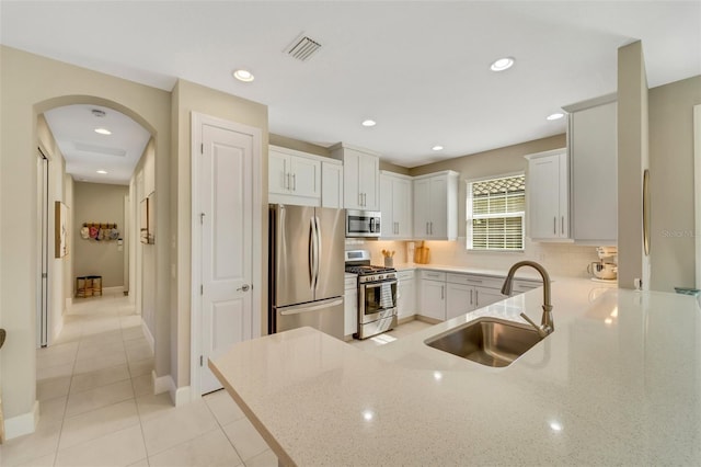 kitchen with white cabinetry, kitchen peninsula, sink, and appliances with stainless steel finishes