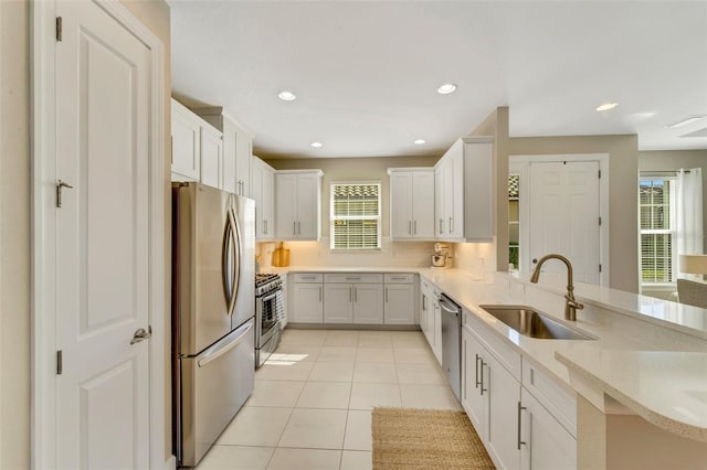 kitchen with kitchen peninsula, stainless steel appliances, white cabinetry, and sink