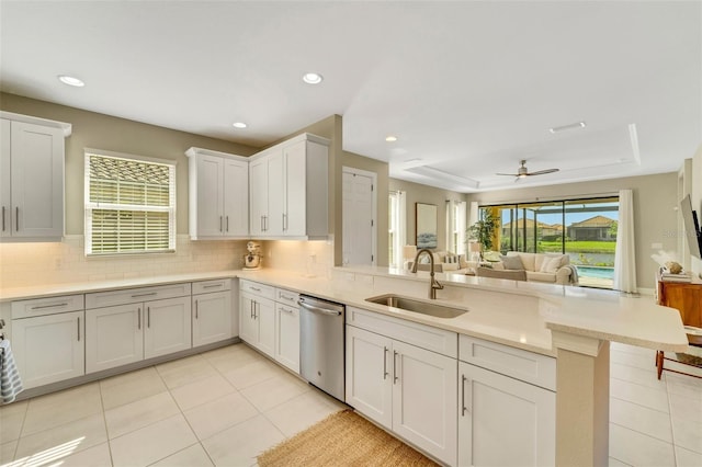 kitchen featuring white cabinetry, sink, a raised ceiling, stainless steel dishwasher, and kitchen peninsula