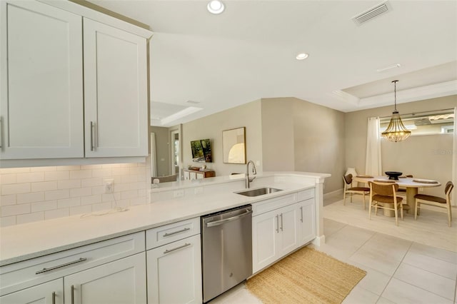 kitchen featuring dishwasher, sink, decorative light fixtures, a tray ceiling, and light tile patterned floors