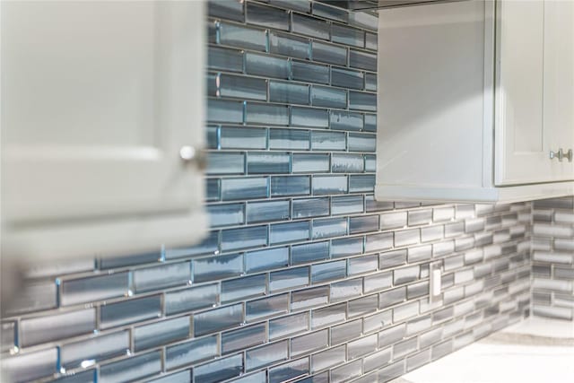 room details featuring decorative backsplash and white cabinetry