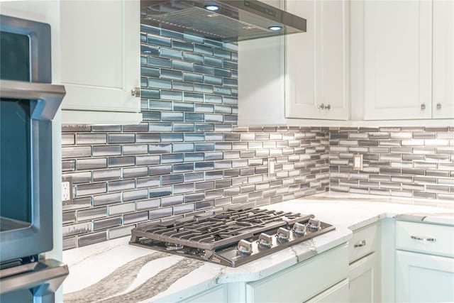 kitchen featuring wall chimney exhaust hood, white cabinetry, stainless steel gas cooktop, and tasteful backsplash