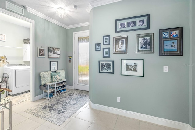 hall featuring a textured ceiling, crown molding, light tile patterned floors, a notable chandelier, and washer / dryer