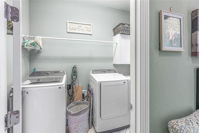 laundry room featuring washer and clothes dryer and cabinets