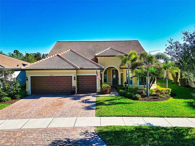 mediterranean / spanish house with a front lawn and a garage