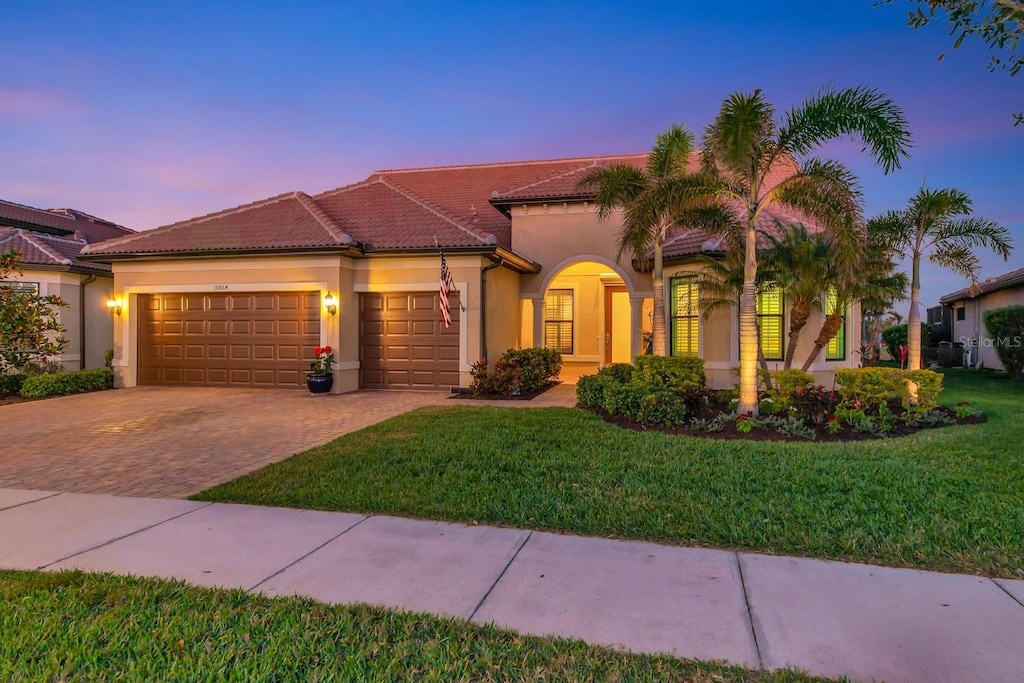 mediterranean / spanish-style home featuring a garage and a lawn