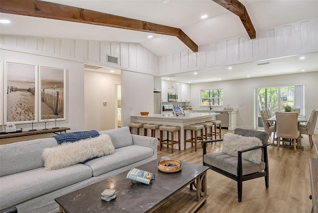 living room with lofted ceiling with beams and light hardwood / wood-style floors