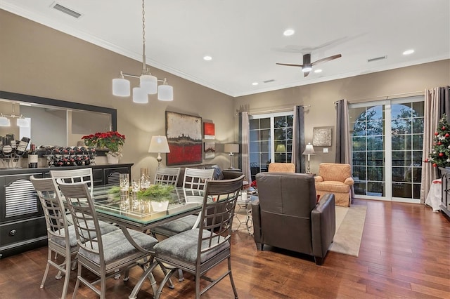 dining space featuring ceiling fan with notable chandelier, crown molding, and dark wood-type flooring