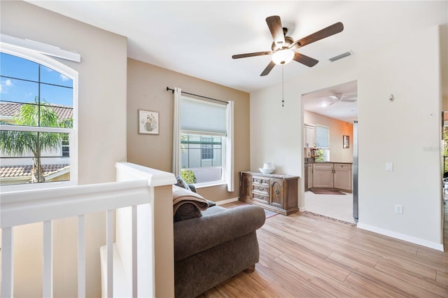 bedroom with ensuite bathroom, ceiling fan, light hardwood / wood-style flooring, and multiple windows