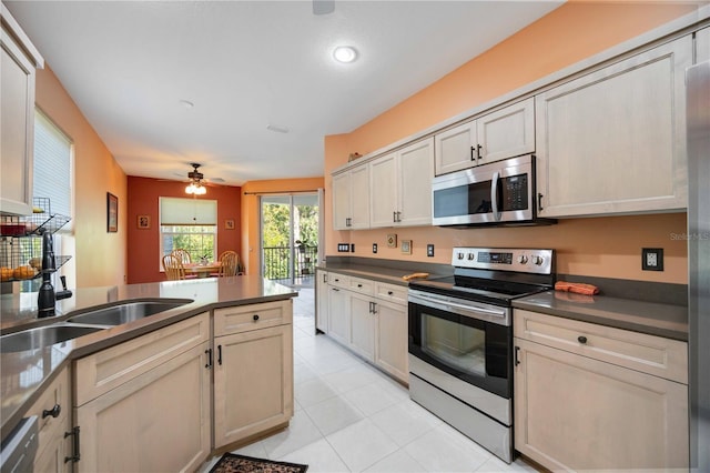 kitchen featuring appliances with stainless steel finishes, ceiling fan, sink, light tile patterned floors, and cream cabinets