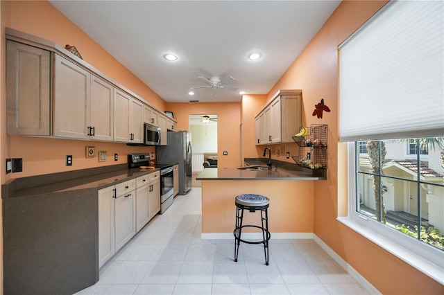 kitchen featuring ceiling fan, sink, kitchen peninsula, a breakfast bar, and appliances with stainless steel finishes