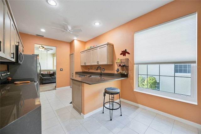 kitchen featuring a kitchen bar, kitchen peninsula, ceiling fan, and sink