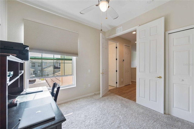 carpeted office space featuring ceiling fan