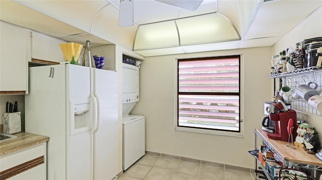 clothes washing area with light tile patterned floors and stacked washer and clothes dryer