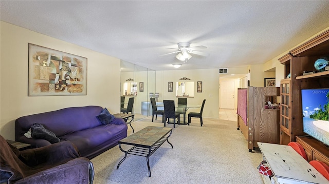 carpeted living room featuring ceiling fan and a textured ceiling