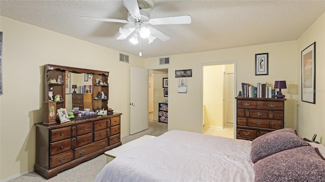 bedroom featuring ensuite bath, ceiling fan, light colored carpet, and a textured ceiling