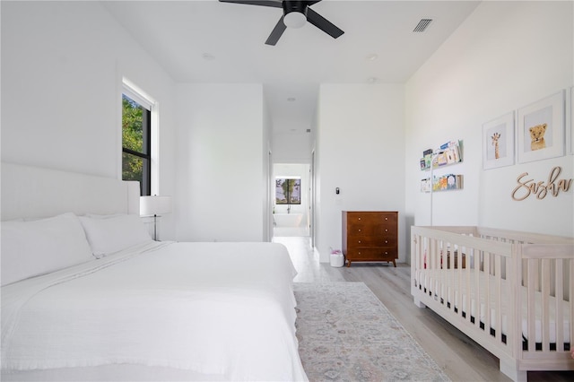 bedroom featuring ceiling fan, ensuite bathroom, and light hardwood / wood-style floors