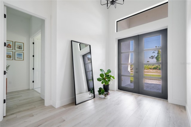 entryway featuring a high ceiling, light hardwood / wood-style flooring, and french doors