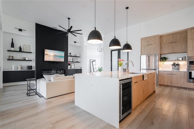 kitchen featuring a large island, light hardwood / wood-style flooring, appliances with stainless steel finishes, decorative light fixtures, and beverage cooler