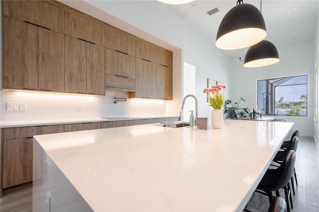 kitchen featuring sink, a breakfast bar, pendant lighting, and a spacious island