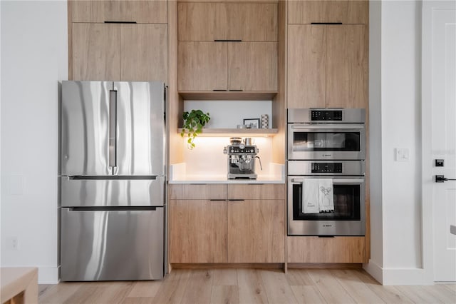 kitchen featuring light wood-type flooring, stainless steel appliances, and light brown cabinets