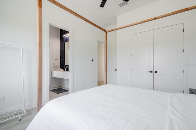 bedroom with ceiling fan, ensuite bath, light hardwood / wood-style floors, and a closet