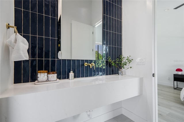 bathroom featuring hardwood / wood-style flooring, sink, and backsplash