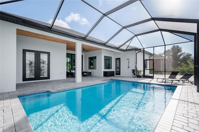 view of swimming pool with glass enclosure, a patio area, ceiling fan, and french doors