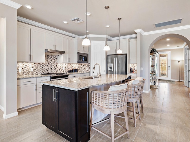 kitchen featuring light stone countertops, sink, stainless steel appliances, pendant lighting, and a center island with sink