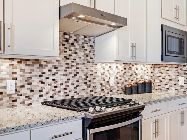 kitchen featuring tasteful backsplash, gas range, built in microwave, and white cabinetry