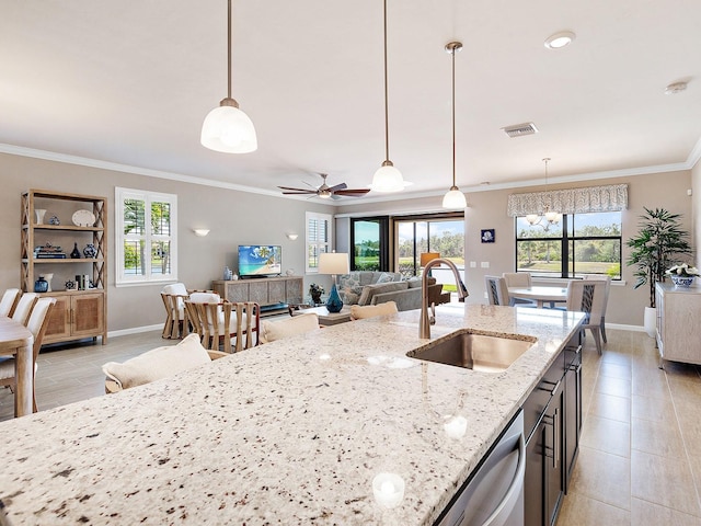 kitchen with light stone counters, ceiling fan, sink, dishwasher, and hanging light fixtures