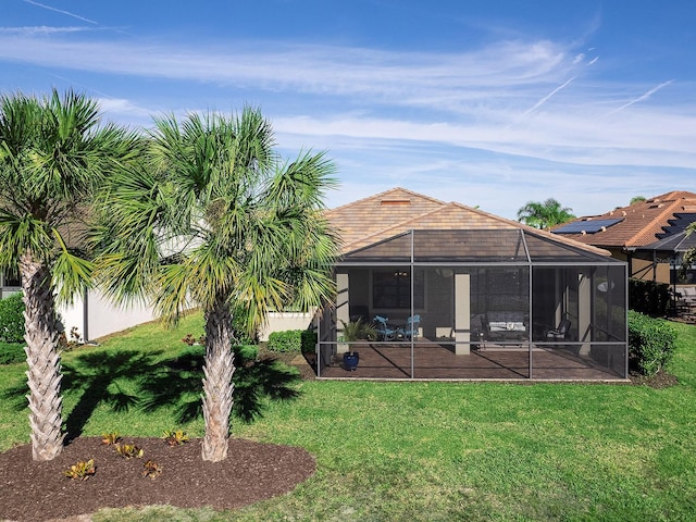 back of property with glass enclosure and a yard