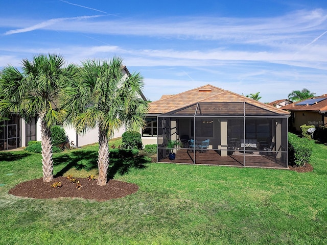 back of property featuring glass enclosure, a patio area, and a lawn