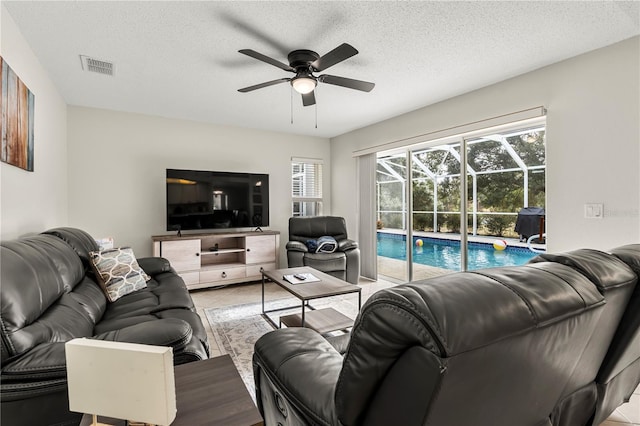 tiled living room with ceiling fan and a textured ceiling