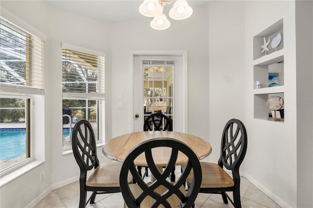 dining area with a wealth of natural light, built in features, light tile patterned flooring, and an inviting chandelier