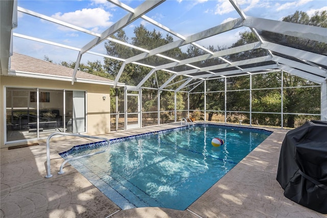 view of pool featuring glass enclosure, grilling area, and a patio area