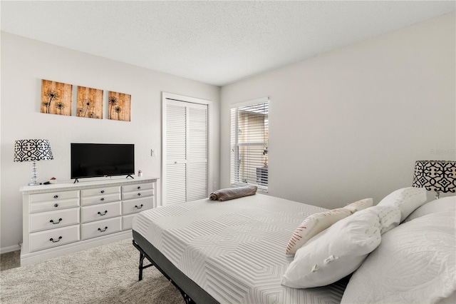 carpeted bedroom featuring a textured ceiling and a closet