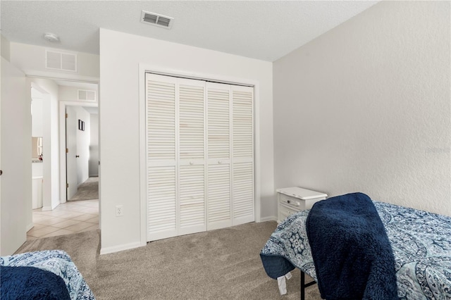 bedroom with light carpet, a closet, and a textured ceiling