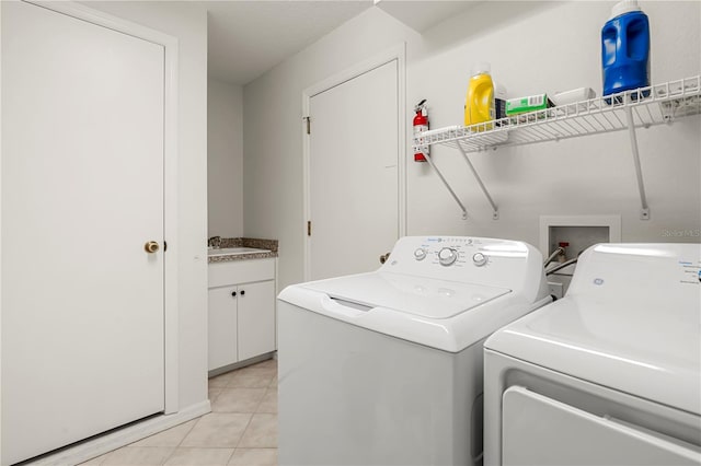 washroom with washer and dryer, light tile patterned flooring, and cabinets